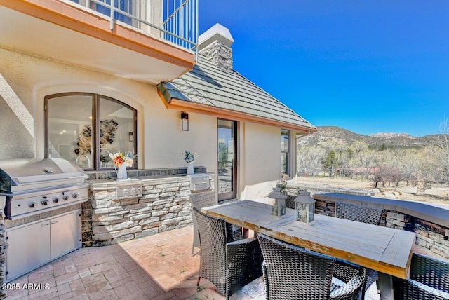 view of patio / terrace featuring exterior kitchen, a balcony, a mountain view, and area for grilling