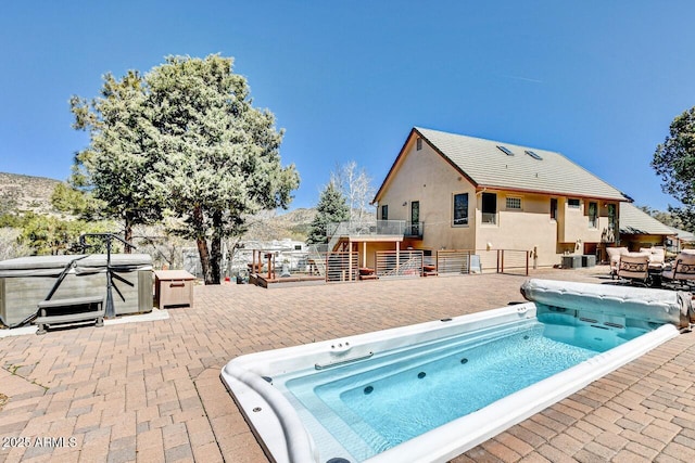 view of swimming pool featuring a mountain view, a patio, and a hot tub