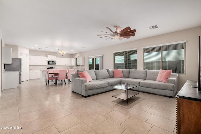 living room featuring light tile patterned flooring and ceiling fan with notable chandelier