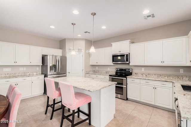 kitchen with stainless steel appliances, a kitchen island, white cabinets, and light stone counters