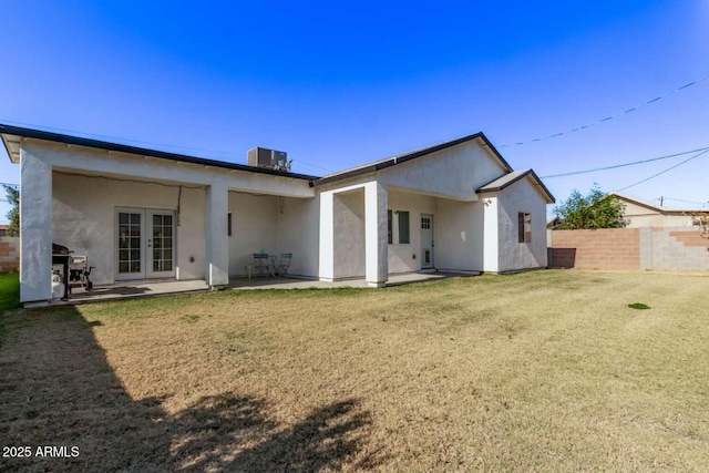 rear view of house with a lawn, cooling unit, a patio, and french doors