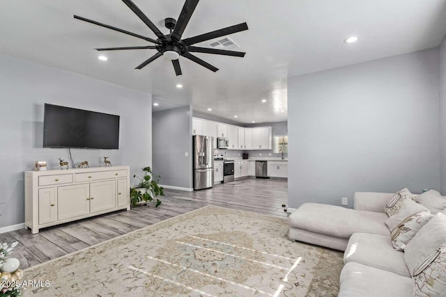 living room with light wood-type flooring and ceiling fan