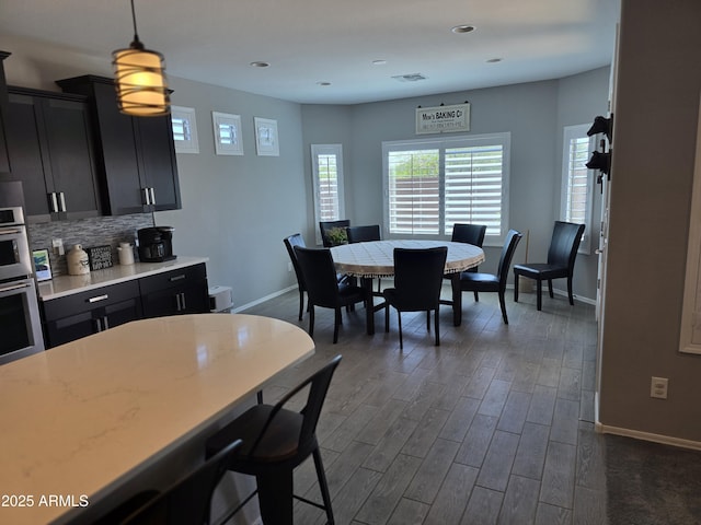 2316 N Crestwood Dr, Florence, AZ 85132 - kitchen featuring backsplash, light countertops, baseboards, dark wood-style floors, and dark cabinets