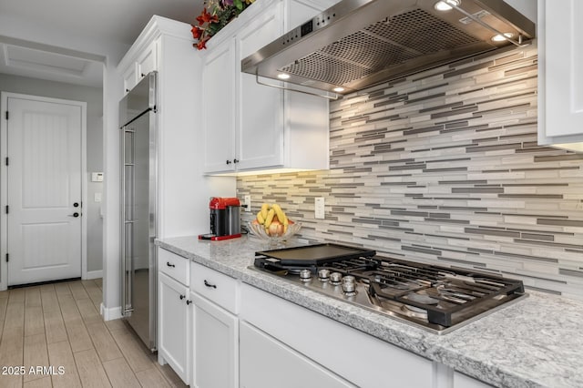 kitchen featuring decorative backsplash, appliances with stainless steel finishes, white cabinets, and premium range hood