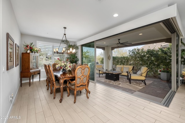 dining space with ceiling fan with notable chandelier and light wood-type flooring