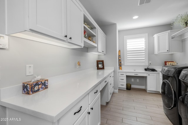 clothes washing area featuring cabinets, light hardwood / wood-style flooring, and washer and dryer