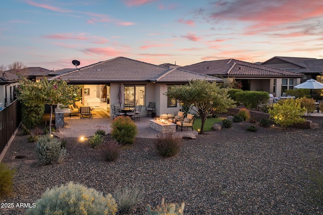 back house at dusk with a patio area and an outdoor living space with a fire pit