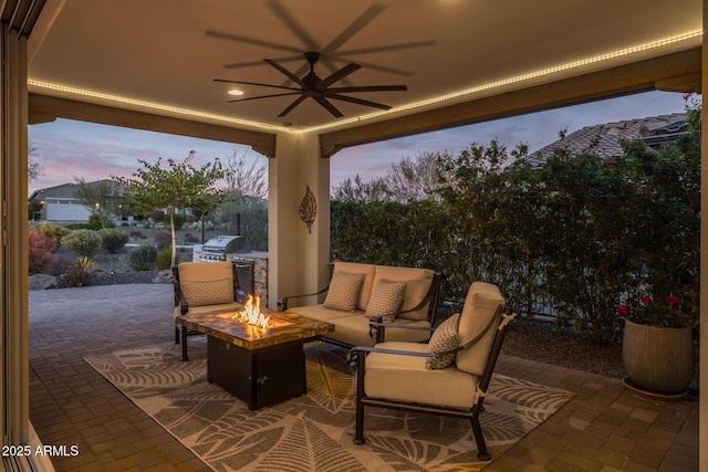 patio terrace at dusk featuring ceiling fan, grilling area, and an outdoor living space with a fire pit