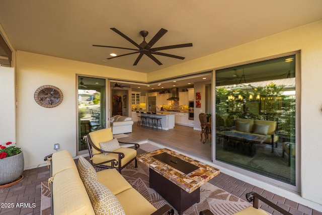 view of patio with ceiling fan and an outdoor living space with a fire pit