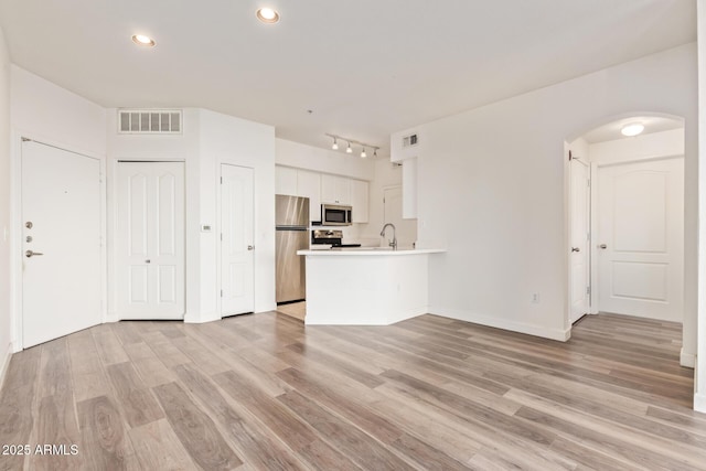 1701 E Colter St Unit 491, Phoenix, AZ 85016 - unfurnished living room with arched walkways, light wood-style flooring, baseboards, recessed lighting, and track lighting