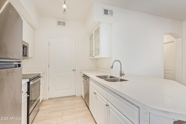 1701 E Colter St Unit 491, Phoenix, AZ 85016 - kitchen with stainless steel appliances, a sink, a peninsula, white cabinetry, and glass insert cabinets