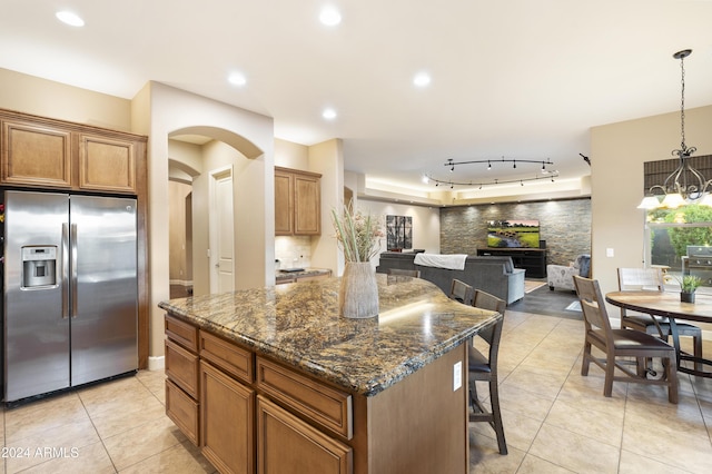 2378 N 158th Dr, Goodyear, AZ 85395 - kitchen with stainless steel fridge, a kitchen island, light tile patterned flooring, arched walkways, and open floor plan