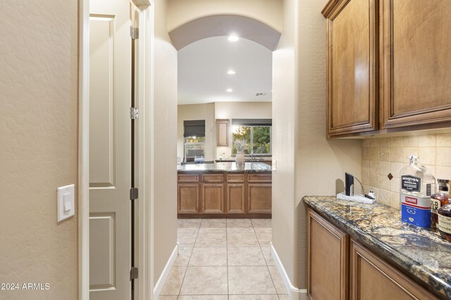 2378 N 158th Dr, Goodyear, AZ 85395 - bar with backsplash, arched walkways, baseboards, light tile patterned floors, and a textured wall