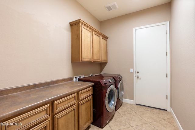 laundry room with washer and clothes dryer, cabinets, and light tile patterned floors