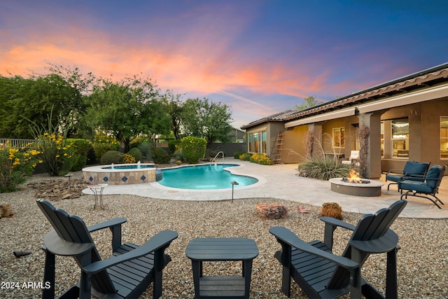 pool at dusk featuring a fire pit, pool water feature, an in ground hot tub, and a patio area