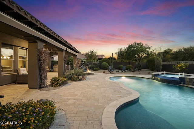 2378 N 158th Dr, Goodyear, AZ 85395 - pool at dusk featuring a patio, a fenced backyard, and a pool with connected hot tub