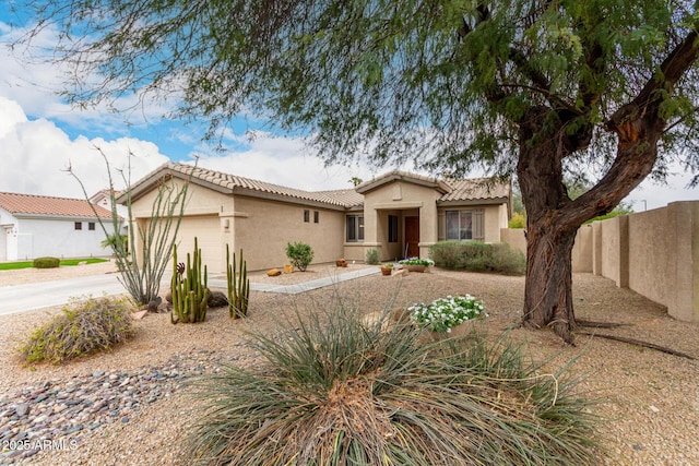 mediterranean / spanish-style home with fence, a tiled roof, stucco siding, driveway, and an attached garage