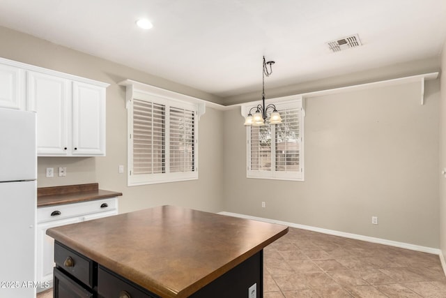 kitchen featuring visible vents, dark countertops, white cabinets, and freestanding refrigerator