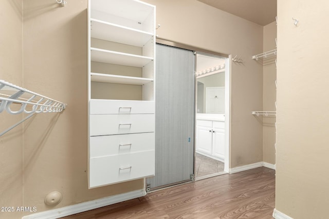 walk in closet with wood finished floors