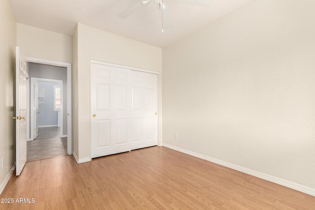 unfurnished bedroom with a closet, baseboards, a ceiling fan, and light wood finished floors