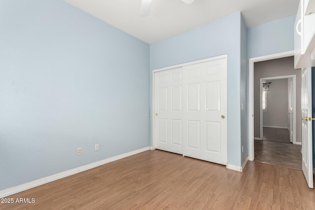 unfurnished bedroom with a closet, a ceiling fan, light wood-type flooring, and baseboards