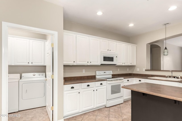 kitchen with dark countertops, a sink, white appliances, white cabinetry, and separate washer and dryer