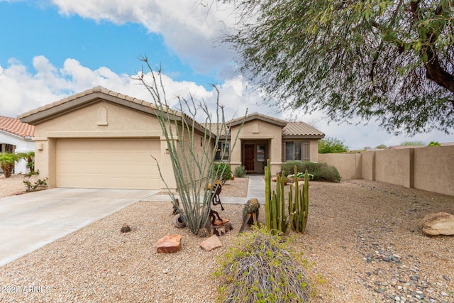 view of front of house featuring fence, a tile roof, concrete driveway, stucco siding, and a garage