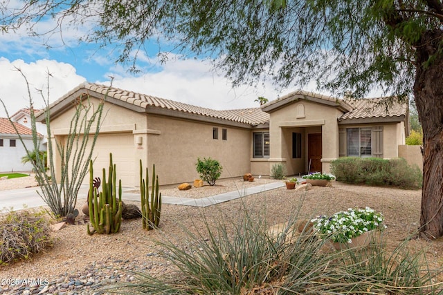 view of front of property featuring stucco siding, a tiled roof, driveway, and a garage