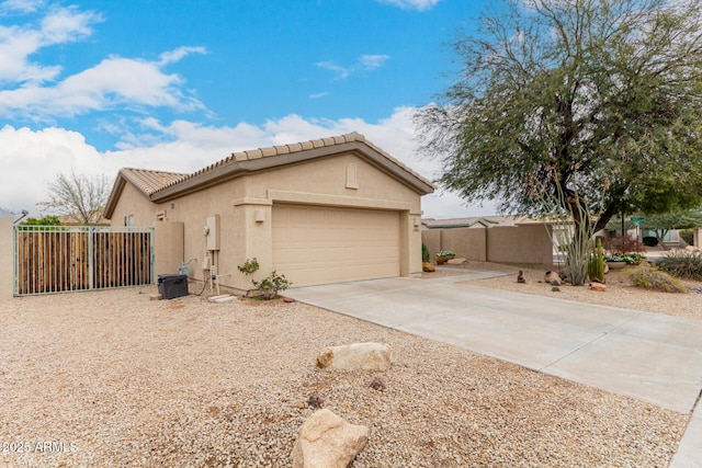 view of side of property with stucco siding, driveway, a tile roof, fence, and an attached garage