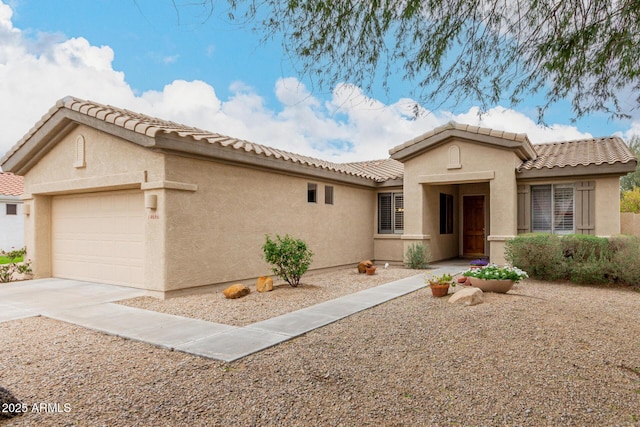 view of front of home featuring a tiled roof, a garage, driveway, and stucco siding