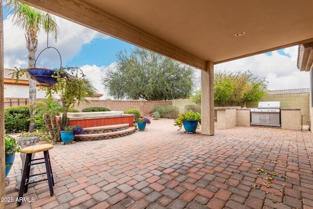 view of patio featuring an outdoor kitchen, a grill, a hot tub, and a fenced backyard