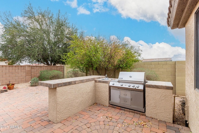 view of patio with a fenced backyard, area for grilling, and an outdoor kitchen