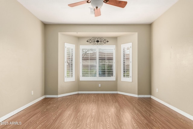 spare room featuring visible vents, baseboards, wood finished floors, and a ceiling fan