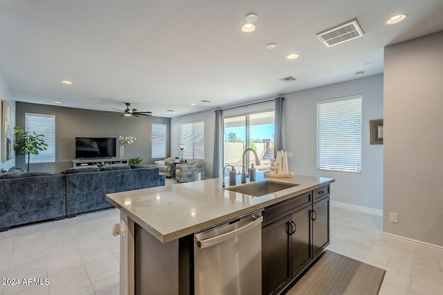 kitchen featuring dishwasher, a kitchen island with sink, sink, ceiling fan, and light stone countertops