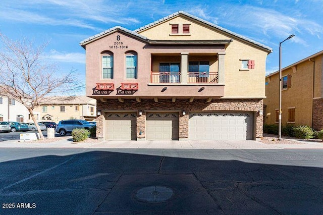 view of front of property featuring a balcony, an attached garage, a tiled roof, and stucco siding