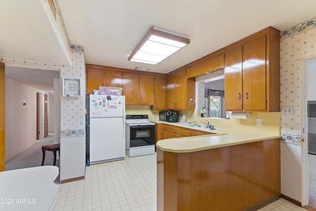 kitchen with kitchen peninsula, sink, and white appliances