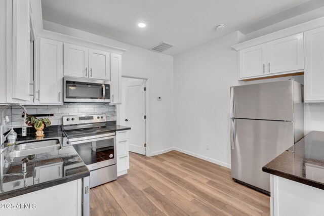 1306 E Fillmore St, Phoenix, AZ 85006 - kitchen featuring stainless steel appliances, a sink, white cabinetry, light wood-style flooring, and tasteful backsplash