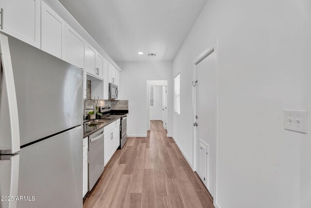1306 E Fillmore St, Phoenix, AZ 85006 - kitchen featuring stainless steel appliances, a sink, backsplash, white cabinetry, and light wood-type flooring