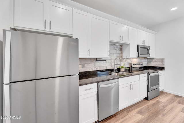 1306 E Fillmore St, Phoenix, AZ 85006 - kitchen featuring appliances with stainless steel finishes, a sink, dark countertops, light wood finished floors, and tasteful backsplash