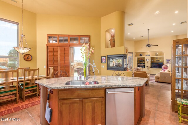 kitchen featuring visible vents, brown cabinets, open floor plan, a sink, and a multi sided fireplace