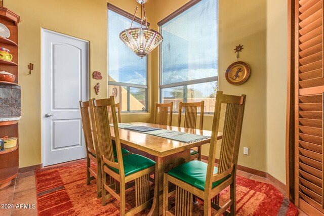 tiled dining room featuring a notable chandelier and baseboards