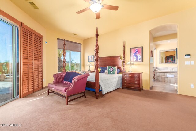 bedroom featuring carpet floors, arched walkways, visible vents, ensuite bathroom, and ceiling fan