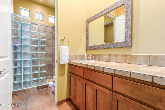 full bath featuring tile patterned flooring, vanity, toilet, and walk in shower