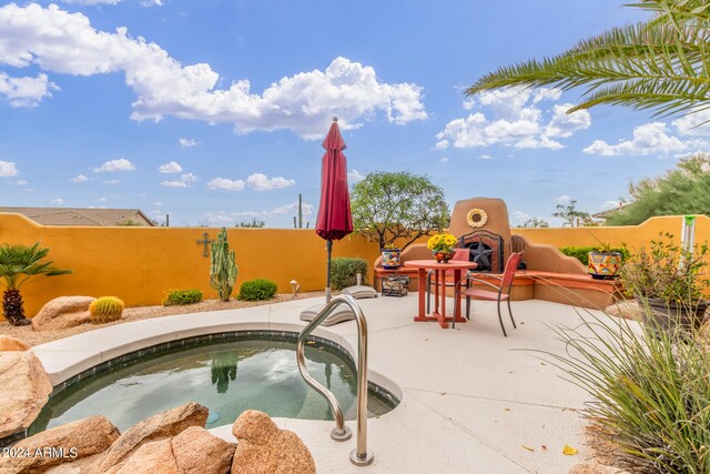 view of pool featuring a patio, a fireplace, fence, and an in ground hot tub