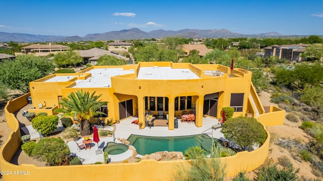 back of house with a pool with connected hot tub, a patio area, a mountain view, and an outdoor living space