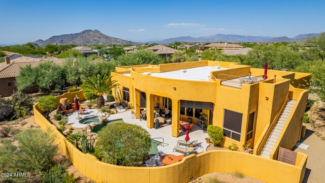 rear view of property featuring an outdoor pool, a patio area, a mountain view, and stucco siding