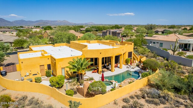 exterior space with a patio, a fenced backyard, a pool with connected hot tub, a mountain view, and stucco siding