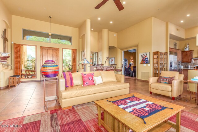 living room with arched walkways, recessed lighting, visible vents, a towering ceiling, and tile patterned floors