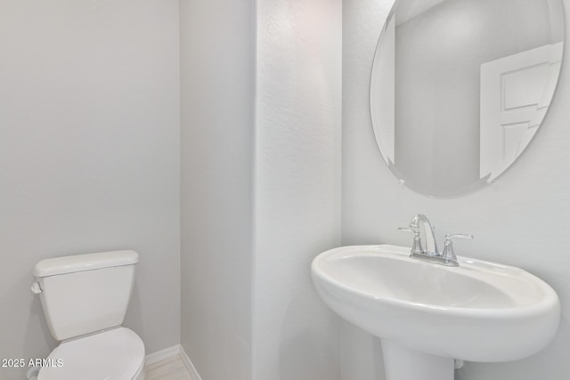 bathroom featuring baseboards, a sink, and toilet