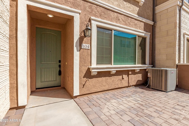 property entrance featuring a patio area, central AC, and stucco siding